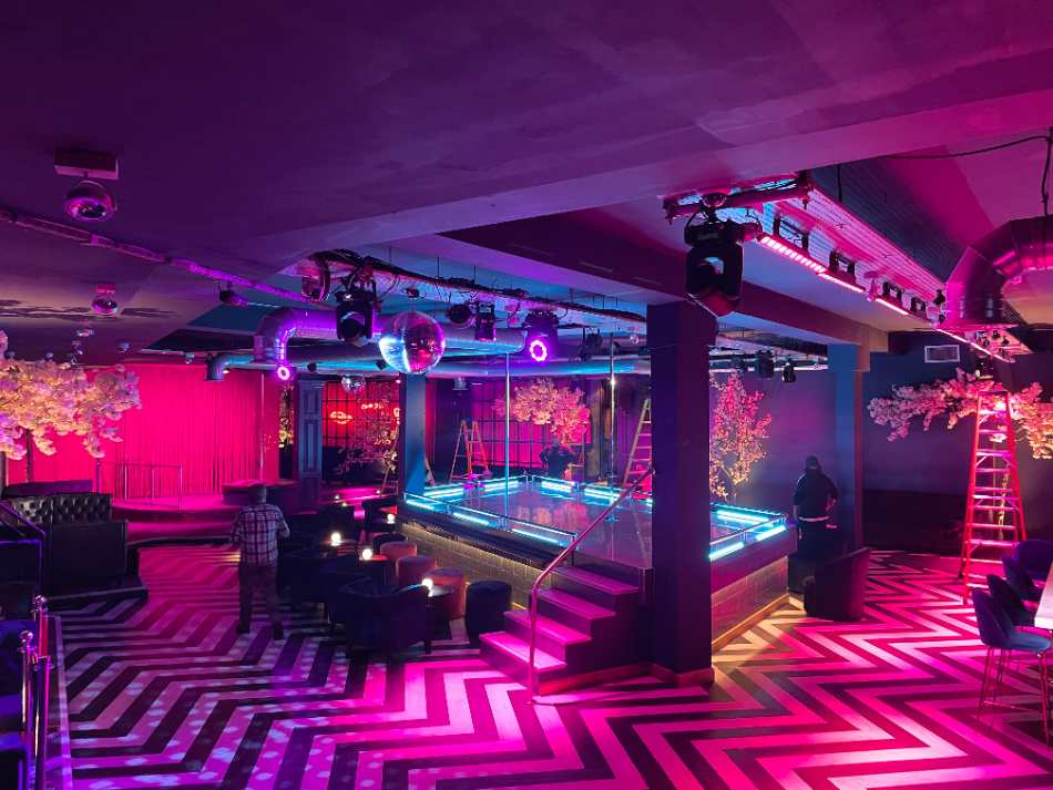 Club room lit in magenta over a chevron floor