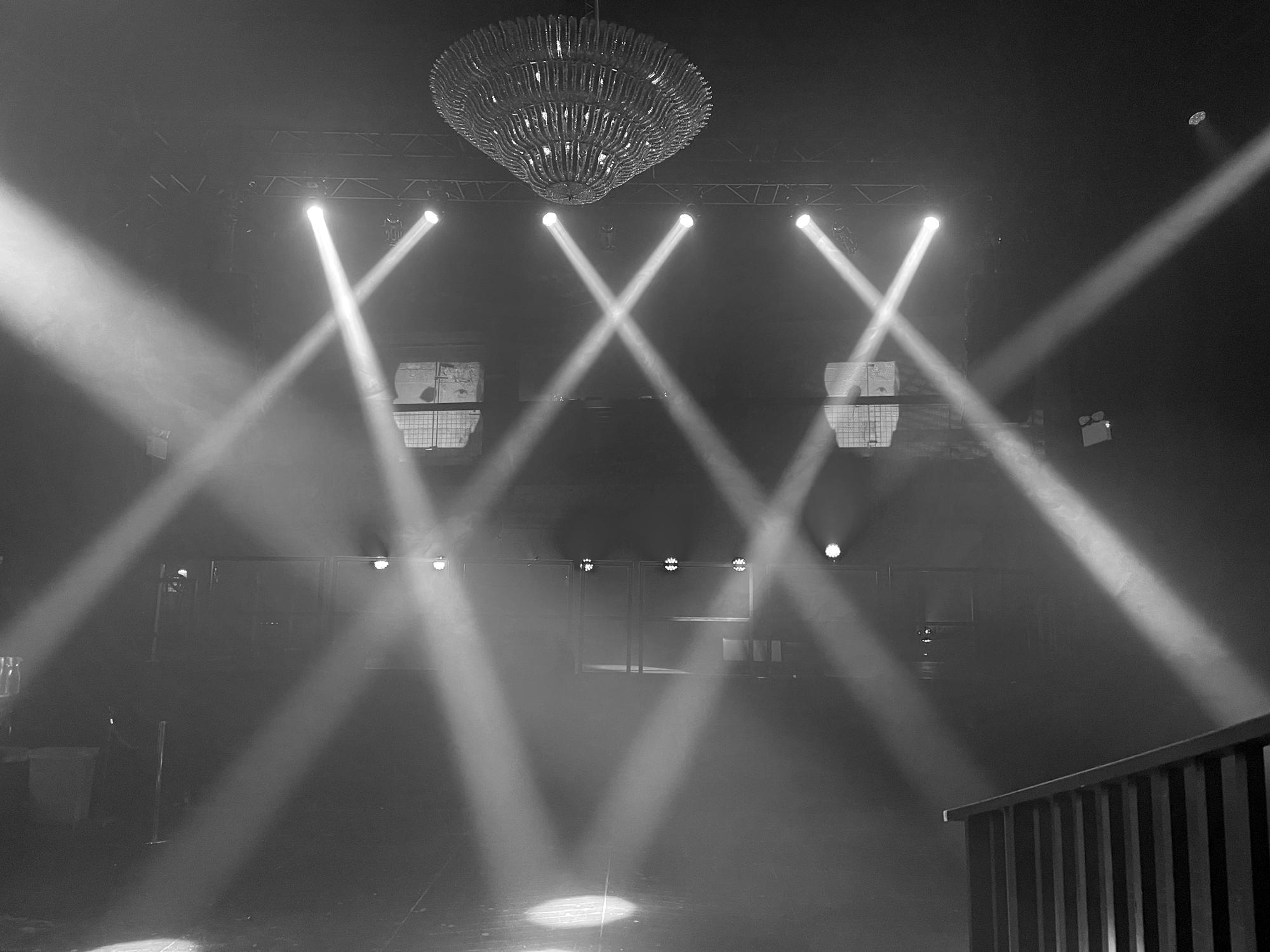 Black and white beams crossing a venue below a chandelier