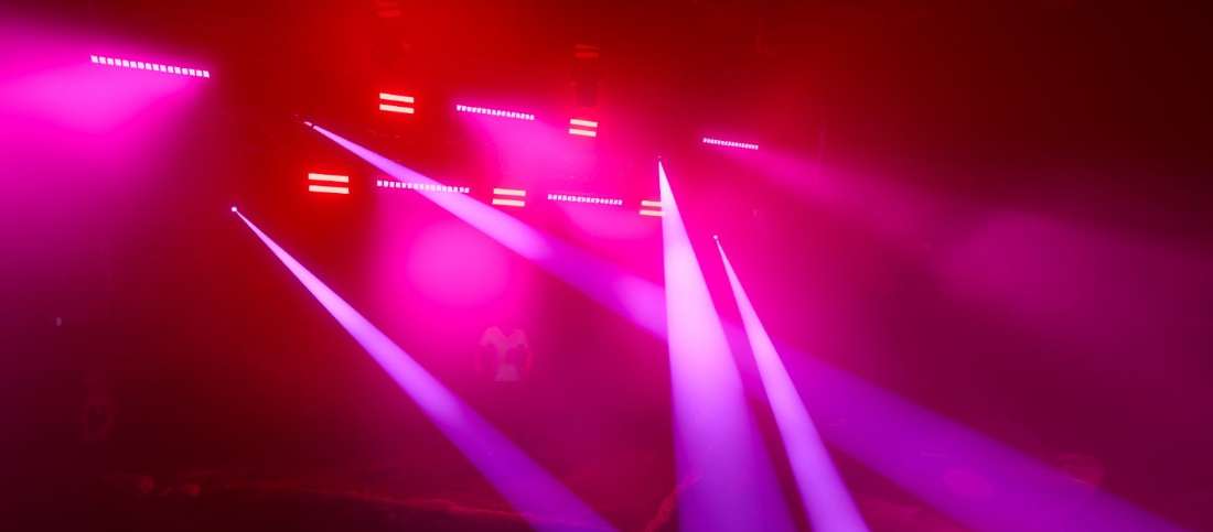 Magenta beams cutting across a dark venue