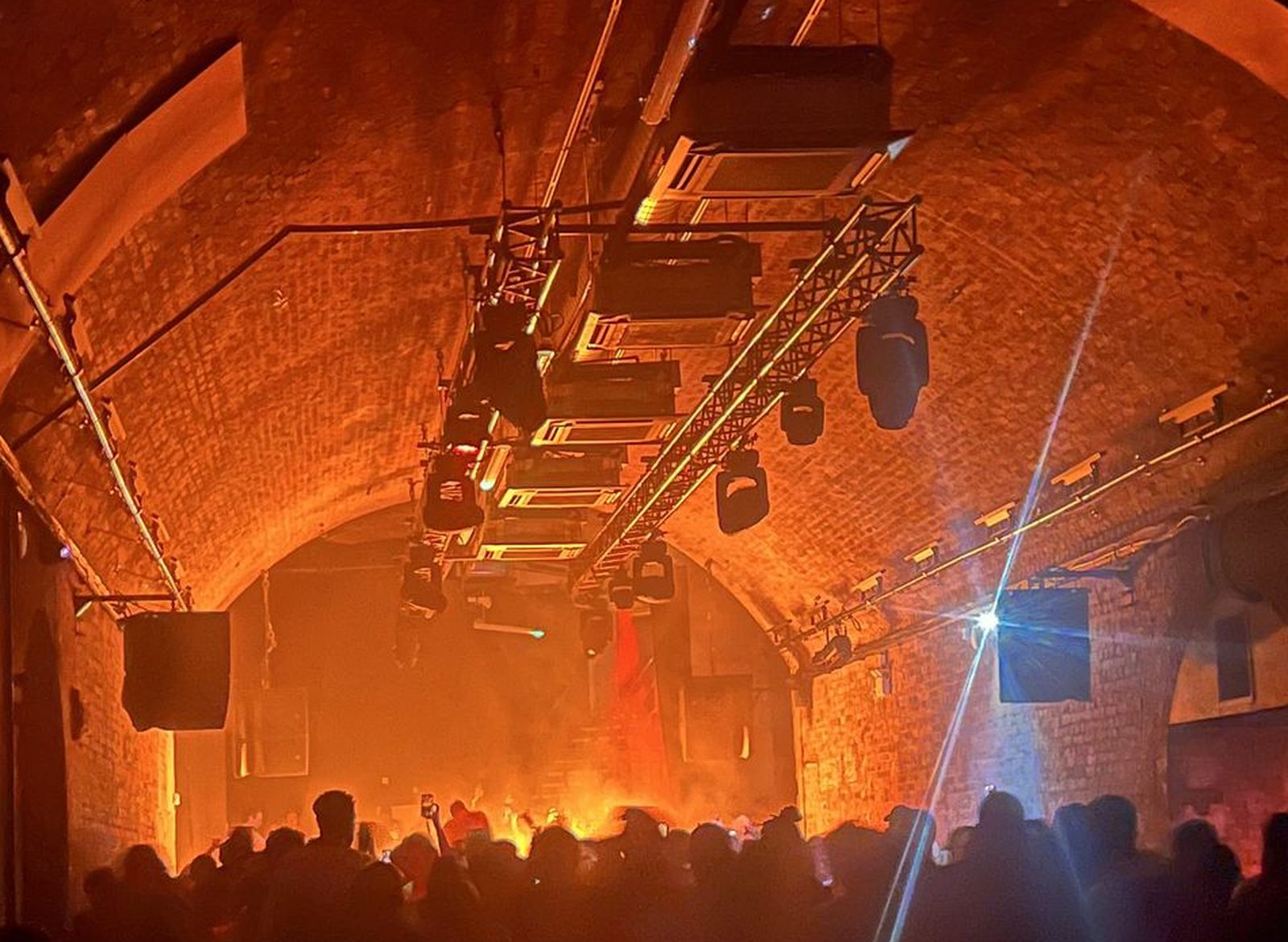 Loudspeakers and truss flown under a brick arch